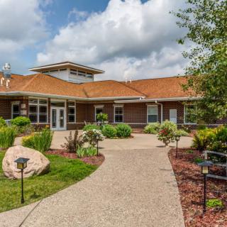 A modern building surrounded by well-maintained landscaping and a clear sky with clouds.