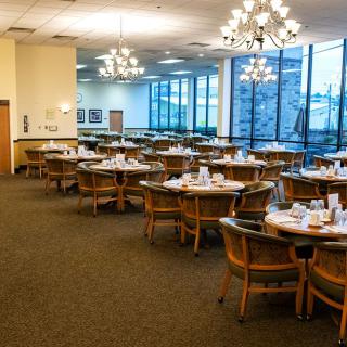 A spacious dining hall with set tables and elegant chandeliers.