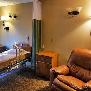 A cozy hospital patient room featuring a bed and an armchair, designed for comfort.
