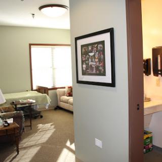 A view of a cozy living room with natural light, featuring a doorway and framed artwork on the wall.