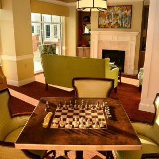 A cozy living room featuring a chess set on a table near a fireplace.