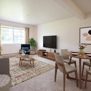 A modern living room with a cozy atmosphere, featuring a television, wooden furniture, and a dining area.