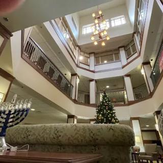 A decorated atrium featuring a menorah and a Christmas tree.
