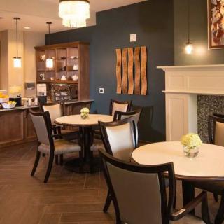 A cozy dining area with elegant interior design, featuring round tables, cushioned chairs, and a modern fireplace.