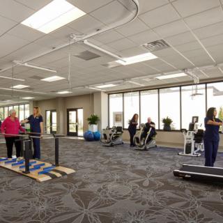 A rehabilitation center with exercise equipment and people engaged in physical therapy.