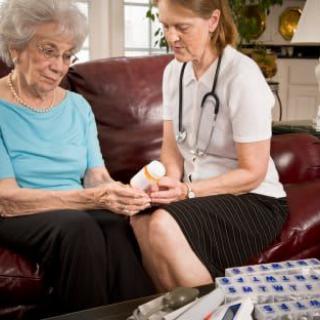 A nurse assists an elderly woman with her medication during a home visit.