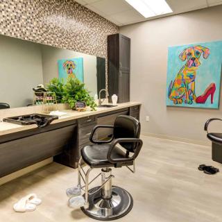 A modern barbershop interior featuring a stylish chair, large mirror, vibrant artwork, and decorative plants.