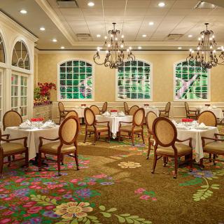 An elegant restaurant dining room with chandeliers and well-arranged tables and chairs.