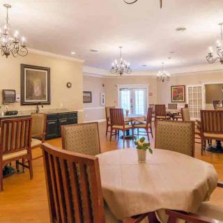 A well-decorated dining area featuring multiple tables and chairs, illuminated by elegant chandeliers.