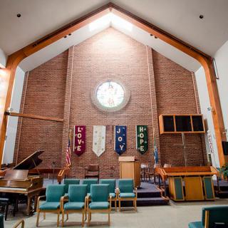 A church sanctuary featuring a pulpit, banners, seating, and musical instruments.