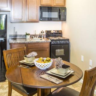 A cozy kitchen setup with a dining table surrounded by chairs and modern appliances.