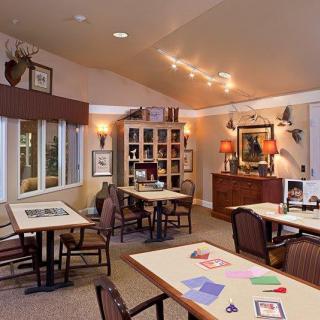 A cozy community room with tables and chairs, decorated with artwork and soft lighting.
