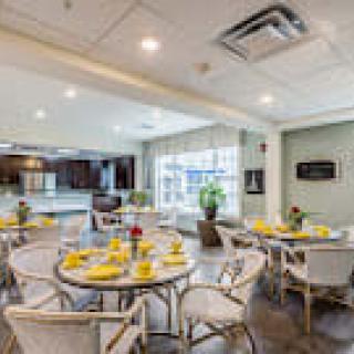 A modern dining area with neatly arranged tables and chairs, adjacent to a kitchen.