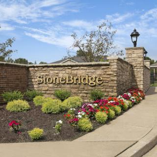 The welcoming entrance of StoneBridge, adorned with vibrant flowers and lush landscaping.