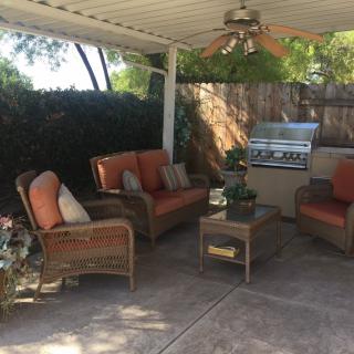 A cozy outdoor patio setup with comfortable seating and a grill.