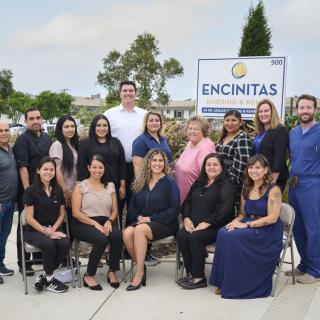 A professional team poses for a group photo in front of a sign that reads 'Encinitas'.