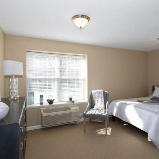 A neatly arranged bedroom with a bed, chair, and a lamp near a window.