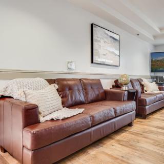 A cozy living room featuring leather sofas, decorative cushions, and a wall-mounted TV.