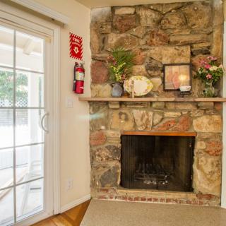 A cozy fireplace with a stone mantel, adorned with decorative items and a nearby sliding glass door.