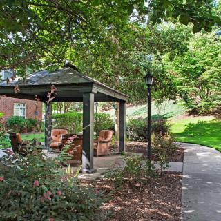 A serene garden with a gazebo and outdoor seating along a winding pathway.