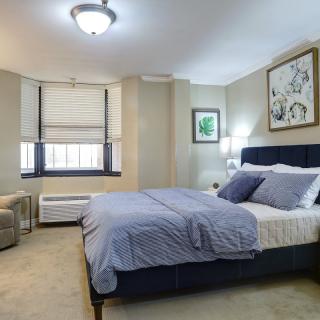 A cozy bedroom with a neatly made bed, two lamps, and framed artwork on the walls.