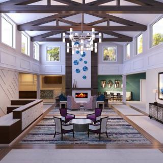 A modern living room with high ceilings, featuring a central fireplace, elegant chandelier, and contemporary seating.
