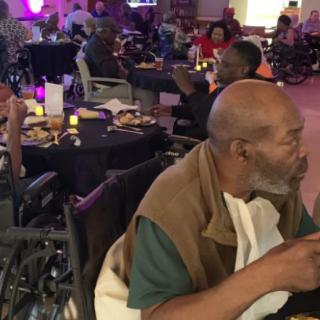 Elderly individuals enjoy a social dining event indoors.