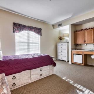 A cozy bedroom with a large window, a bed, and a dresser.