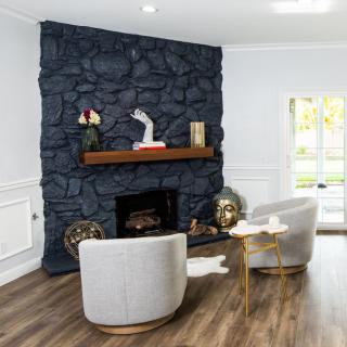 A modern living room featuring a dark stone fireplace, stylish armchairs, and wooden flooring.