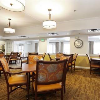 A spacious dining area with neatly arranged tables and chairs, complemented by warm lighting and wooden flooring.