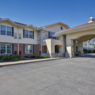 An exterior view of a residential building, possibly an assisted living facility, featuring a covered entrance.