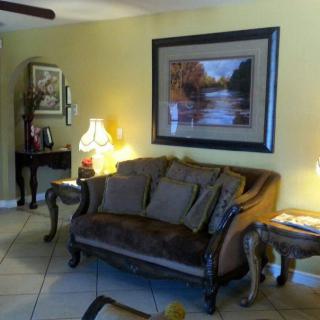 A cozy living room featuring a classic sofa, elegant lamps, and a landscape painting on the wall.