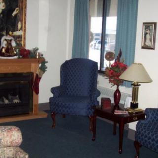 A cozy living room with a fireplace, armchairs, and decorative elements.