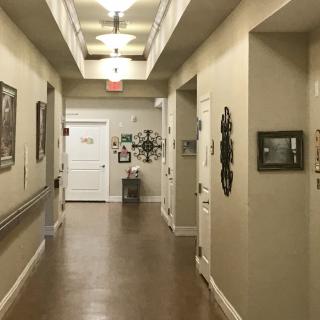 A well-lit hallway with framed decor and multiple doors along its walls.