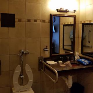 A well-equipped bathroom featuring a toilet, sink, and mirrors, designed for accessibility.