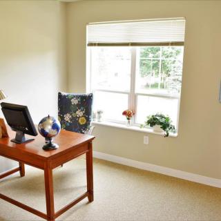 A cozy office space with a desk and computer near a bright window.
