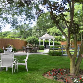 A serene garden featuring a gazebo surrounded by lush greenery and outdoor furniture.