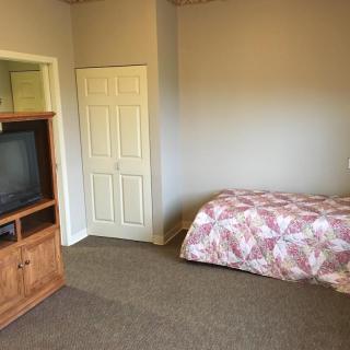 A simple bedroom with a bed, television, and minimal furnishings.