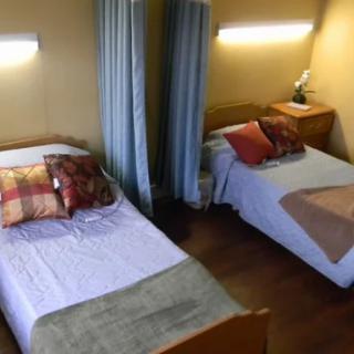 A cozy bedroom with two twin beds, adorned with pillows and soft lighting.