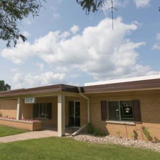 A brick building with a well-maintained lawn under a partly cloudy sky.