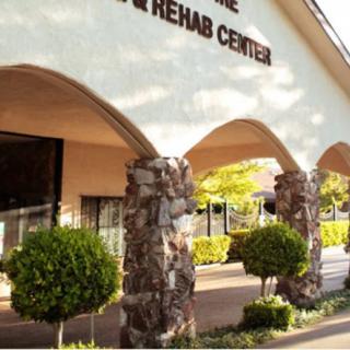 Entrance to a rehab center featuring arches and manicured shrubs.