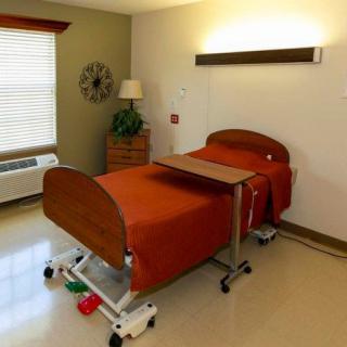 A clean and well-organized hospital room with a single bed and medical equipment.