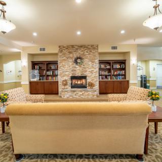 A cozy living room with a central fireplace, surrounded by bookshelves and comfortable seating.