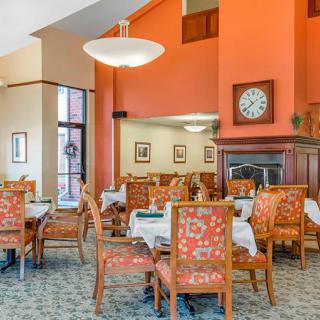 A warmly decorated dining area with orange walls, featuring tables and chairs neatly arranged.