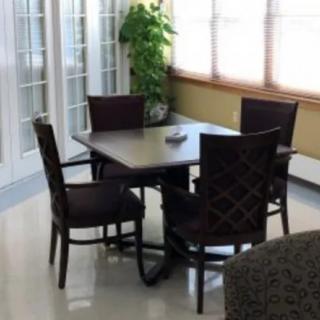A well-lit indoor dining area with a square table and four chairs.