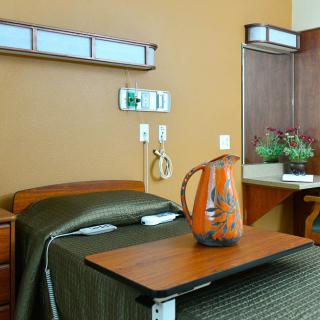 A comfortable hospital room with a single bed and bedside table.