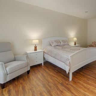 A cozy bedroom featuring a comfortable bed with a nightstand on each side, accompanied by an armchair and warm lighting.