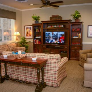 Cozy living room with a television, plaid sofas, and wooden furniture.