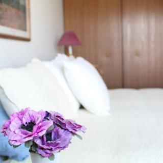 A cozy bedroom featuring soft pillows and a decorative flower arrangement.