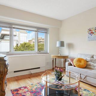 A cozy living room with a sofa, coffee table, and large window letting in natural light.